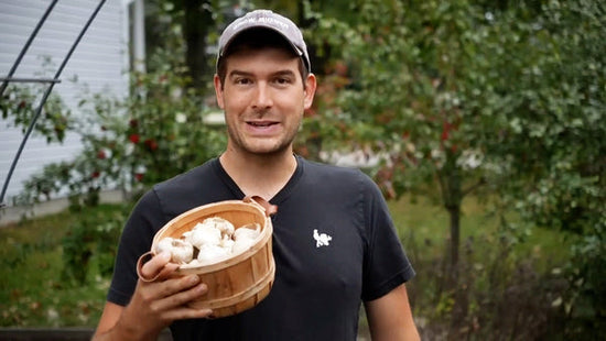 A man holding a basket of fresh garlic.